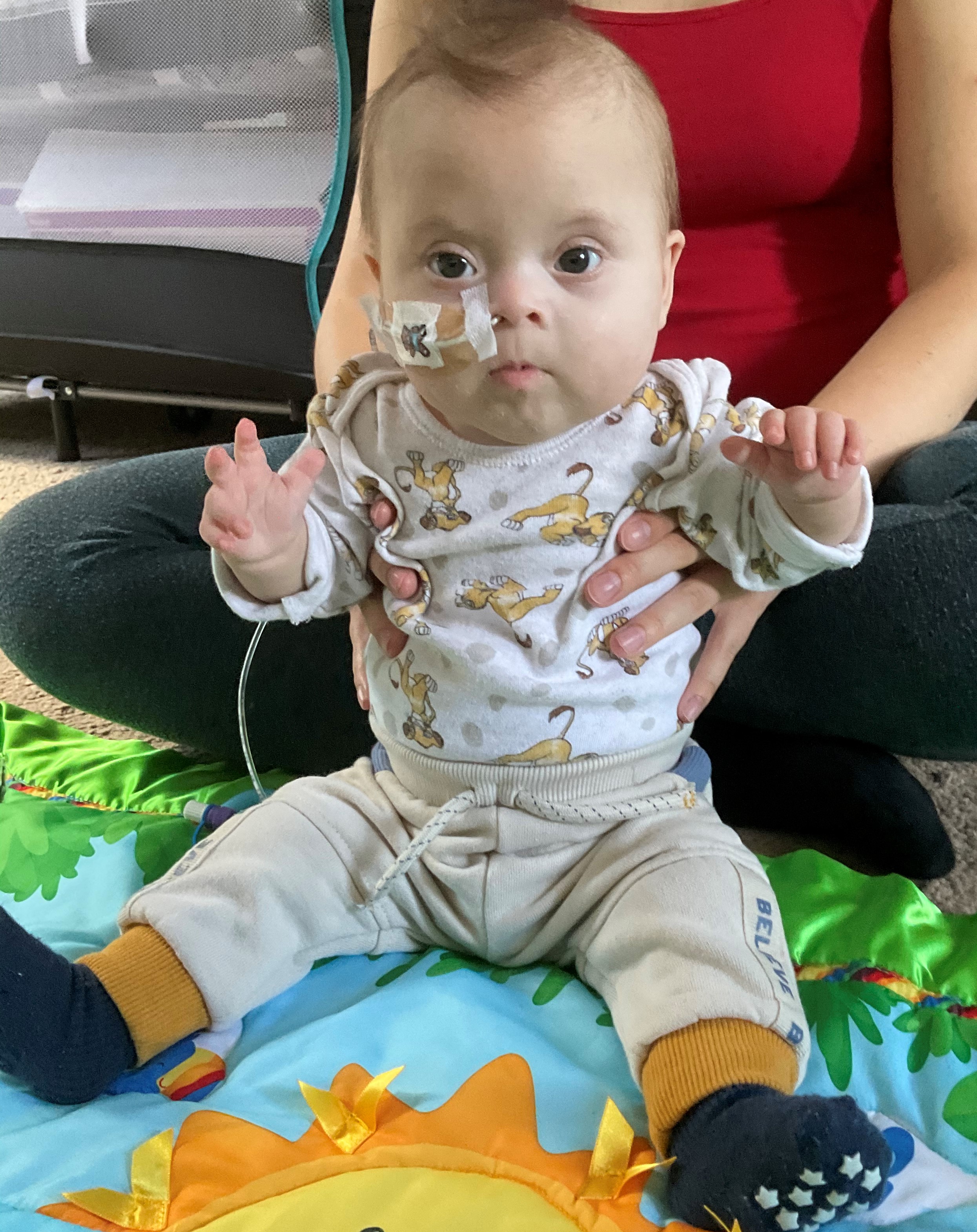 Baby practising supported sitting with head control from their parent