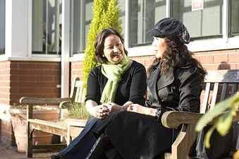 two women chatting on a bench